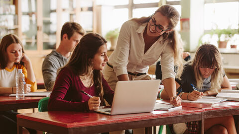 Lehrerin im Unterricht im Gespräch mit einer Schülerin
